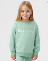 Свитшот оверсайз светло-зеленый Button Blue APT. 123BBGB16014800: Светло-зеленый базовый свитшот для девочки с округлой горловиной и оригинальным текстовым принтом подарит заряд хорошего настроения и максимальный комфорт в носке. Уютная модель из футера имеет гладкую лицевую сторону и петельчатую изнанку без начеса. Мягкая хлопковая ткань приятна на ощупь, проста в уходе и обеспечивает оптимальную терморегуляцию. Прямой крой изделия способствует свободной и модной посадке oversize. Низ изделия, горловина и манжеты выполнены из эластичной рибовой ткани. Лаконичный текстовый принт на полочке однозначно поднимет юной моднице настроение и позволит ей быть в центре внимания. Детский свитшот мятного оттенка оптимально сочетается с джоггерами, джинсами, лосинами и шортами из коллекций Button Blue.